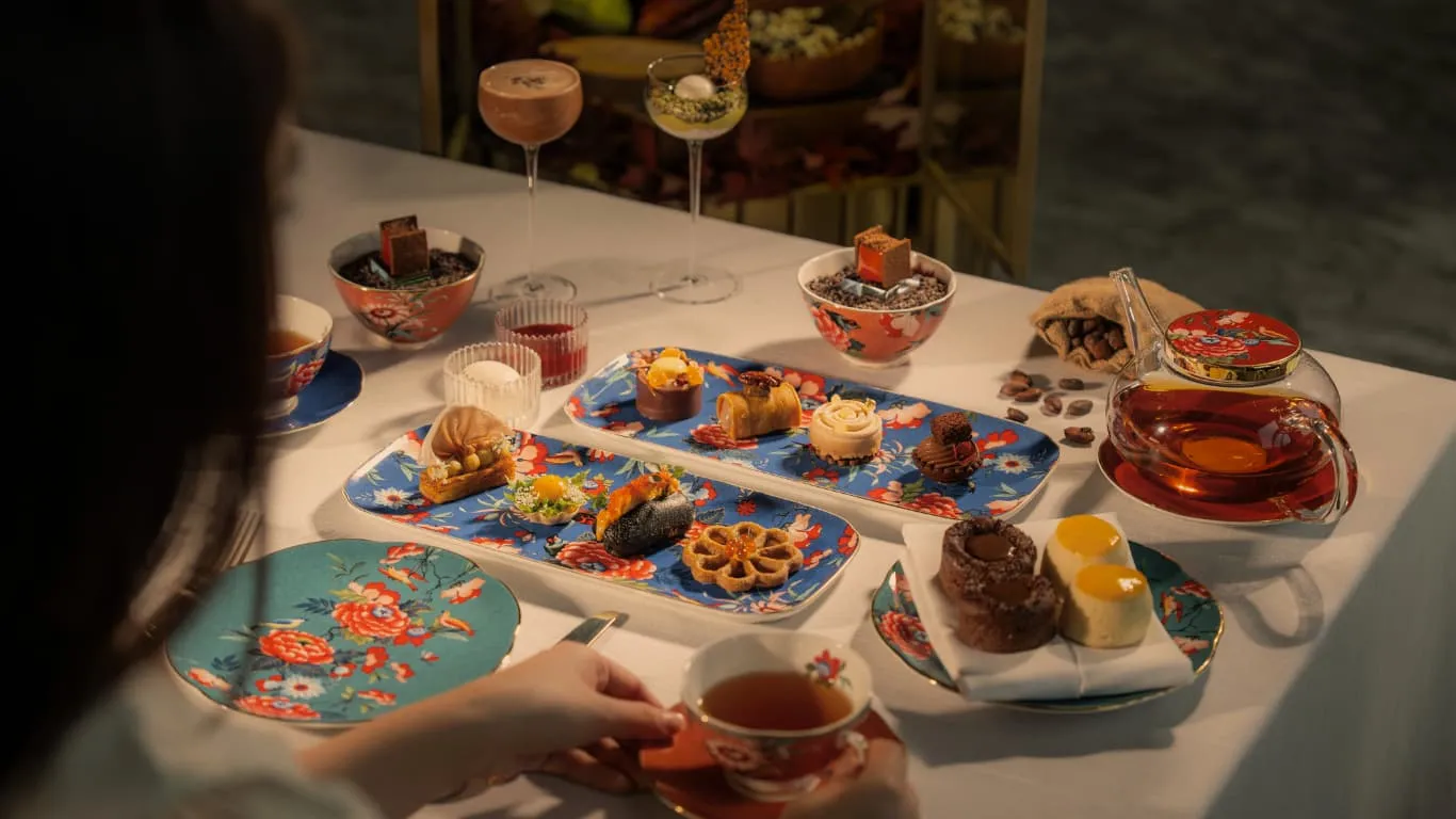 Il tè del pomeriggio del Tea Lounge: dolci e salati su vassoi dipinti, una teiera e una tazza di porcellana a fiori.