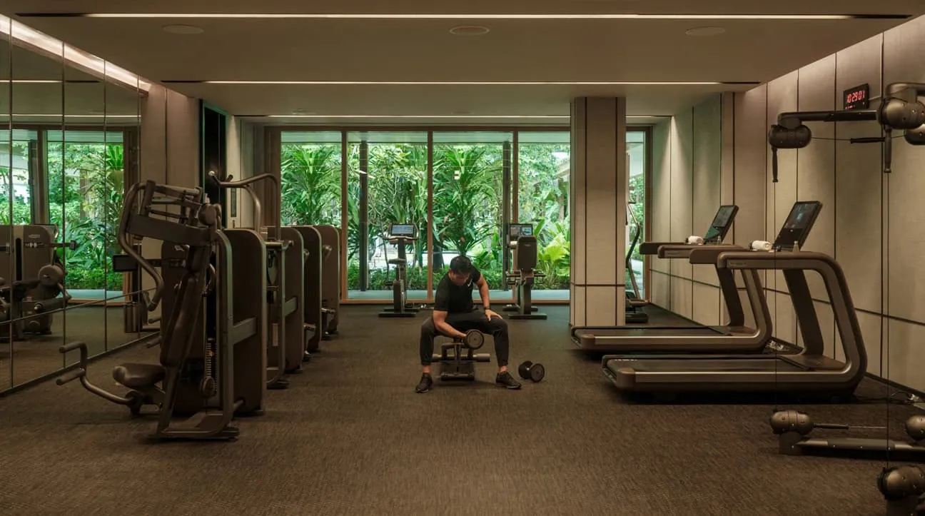 La palestra aperta 24 ore: tapis roulant e macchine davanti alle vetrate sul verde.