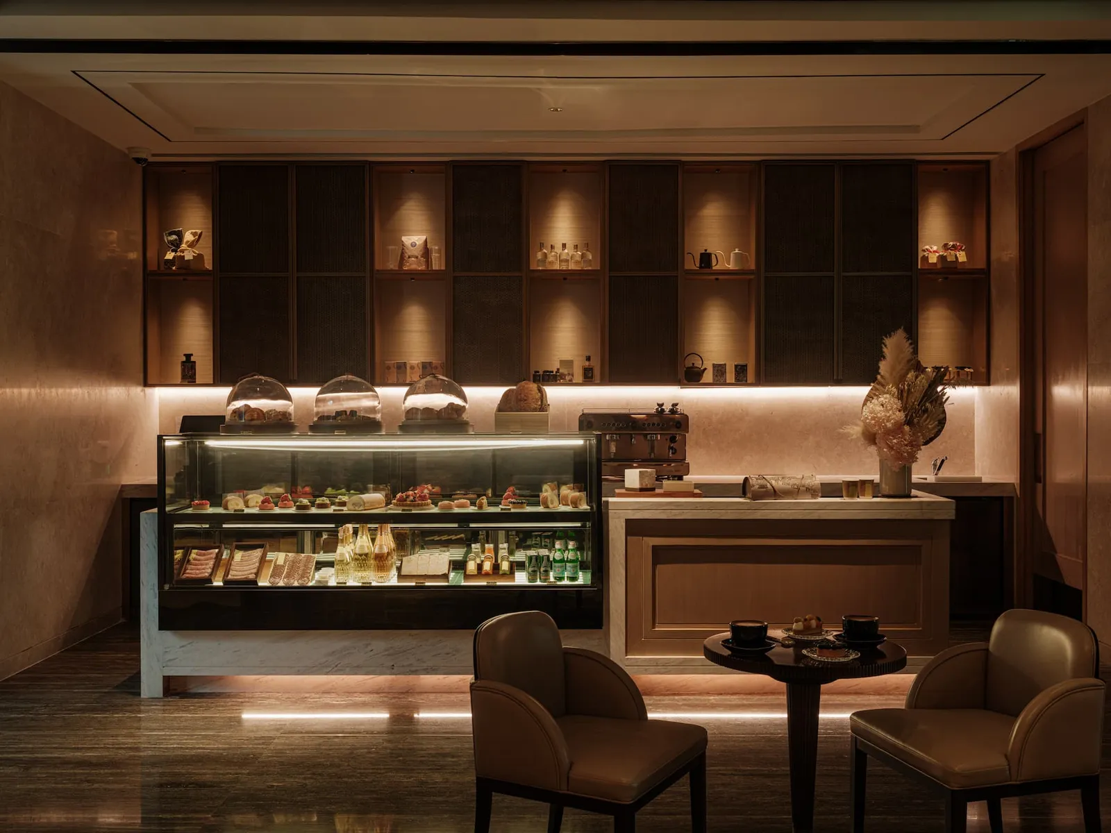 KIN, la pasticceria accanto a Phra Nakhon: la vetrina dei dolci, scaffali illuminati e 2 poltroncine.