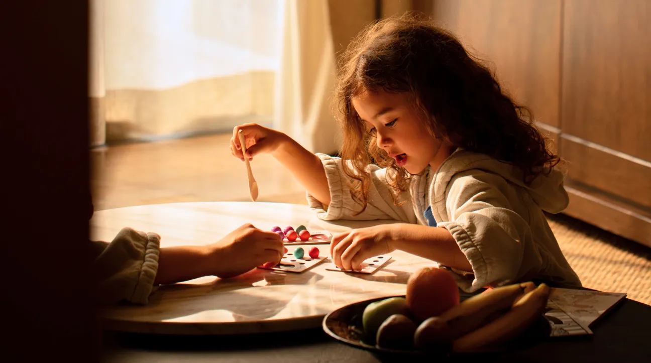 Una bambina dipinge a un tavolo basso, con un vassoio di frutta accanto: il programma Little Stars.