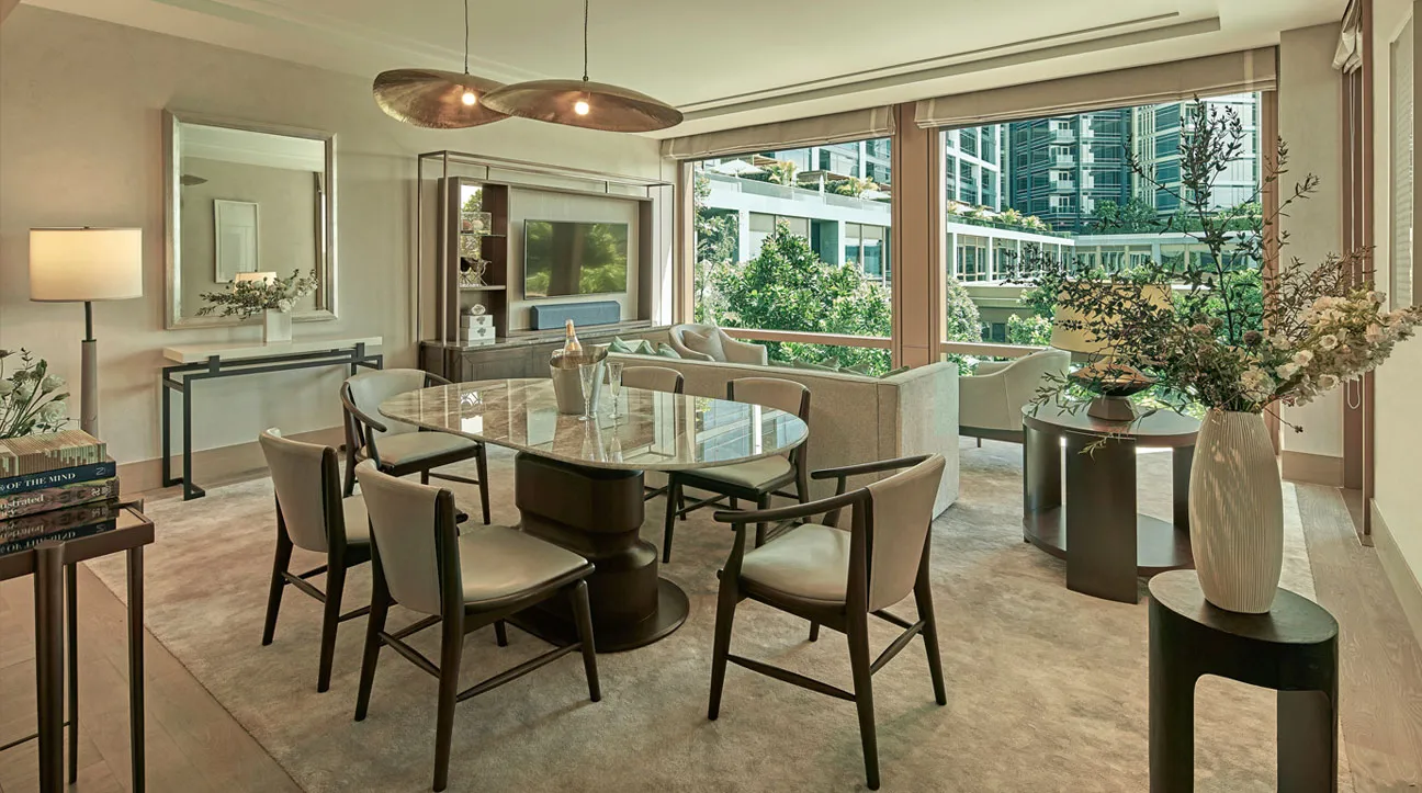 La zona pranzo della 2 Bedroom Family Capella Suite: il tavolo per 6 sotto un lampadario sospeso, le vetrate sugli alberi.