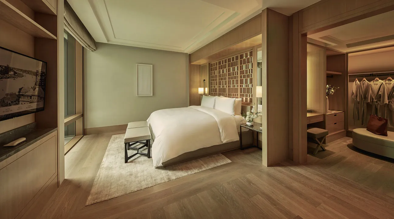 Una camera della 2 Bedroom Family Courtyard Suite: il letto king, la panca ai piedi e la cabina armadio aperta.