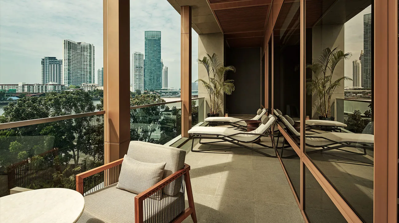 Il balcone che gira attorno a una Capella Suite: chaise longue, piante in vaso e i grattacieli oltre il fiume.