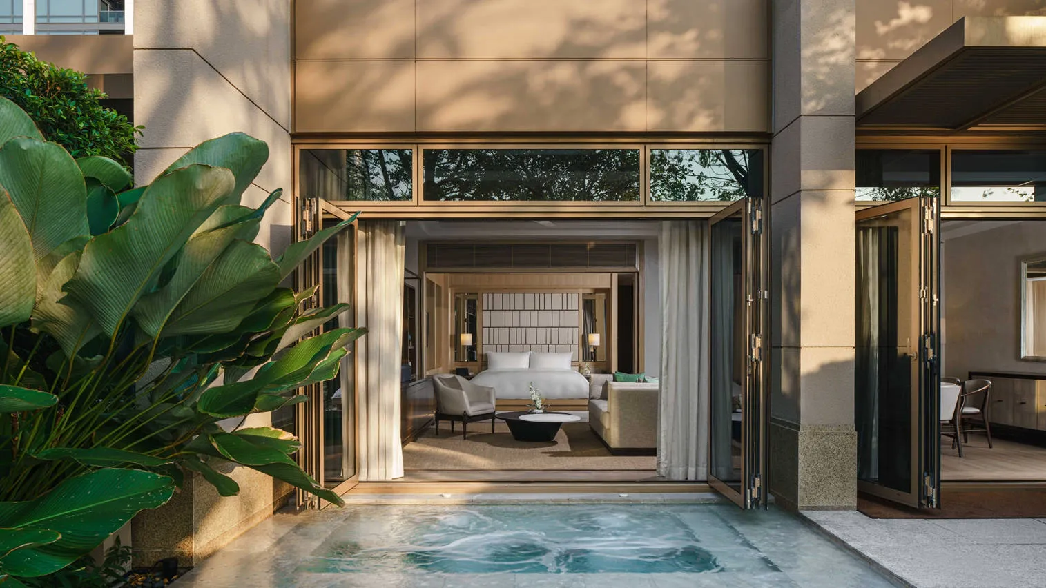 L’ingresso di una Villa dal cortile: la vasca idromassaggio, le piante e la camera oltre le porte a vetri.