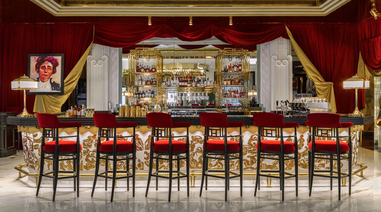 Diva’s Lounge: a gilded bar with red velvet stools and a portrait above it