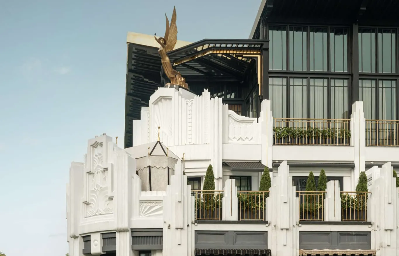 The white Art Deco façade with its balconies, a gilded winged figure on the roof