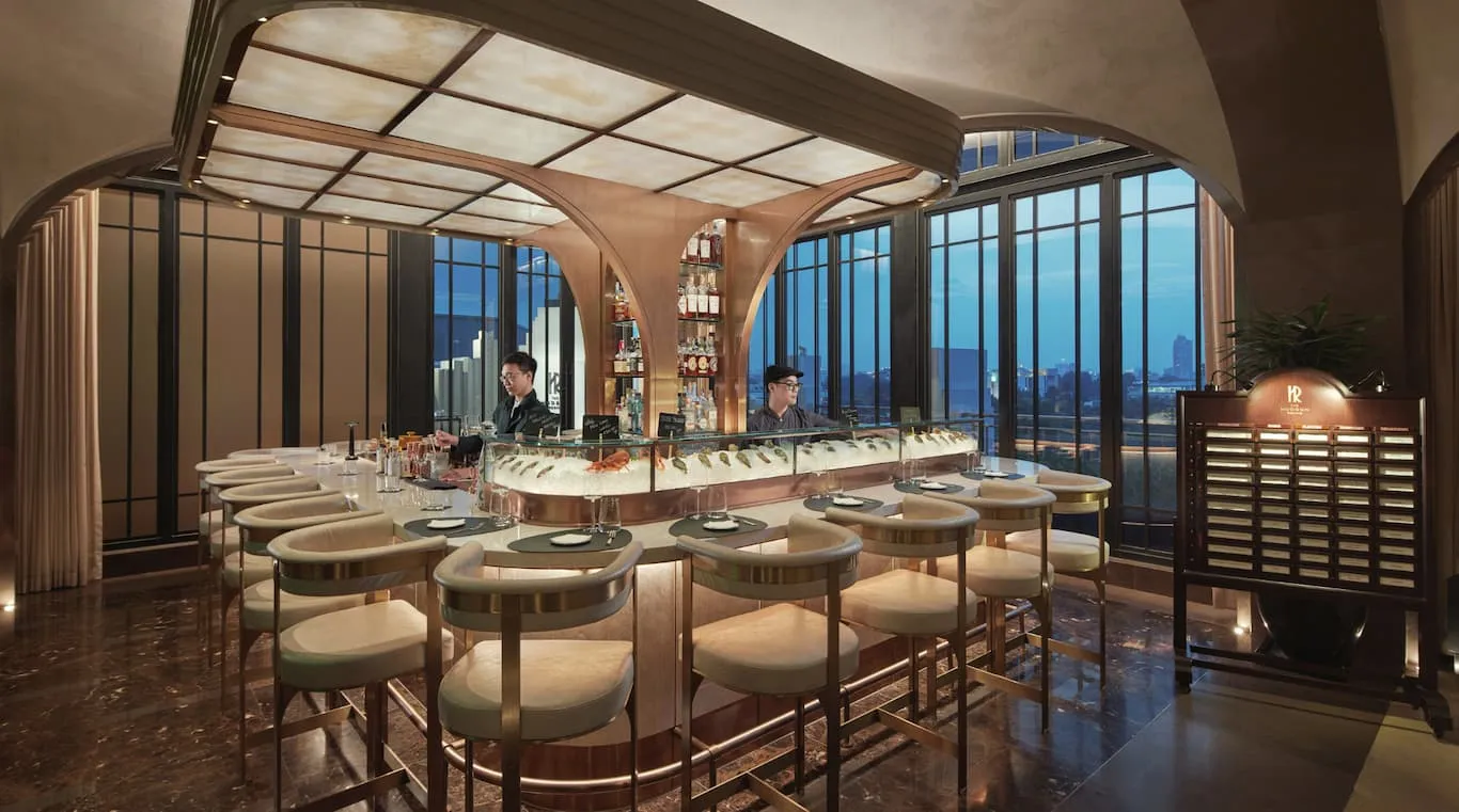 The Hudson Rooms: an oyster bar under a coffered glass ceiling, tall windows on the city