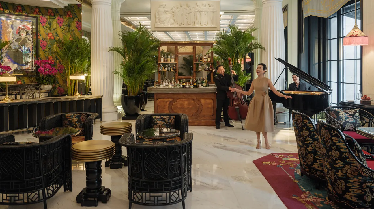 The Living Room: a singer beside the grand piano, palms, marble columns and the bar