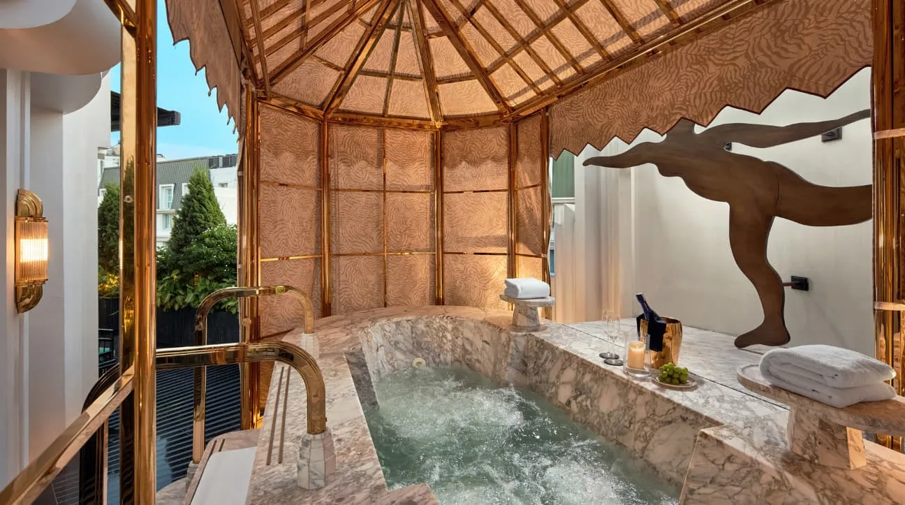 The Grand Opera Suite’s marble jacuzzi under a pavilion, a bronze dancing figure on the wall