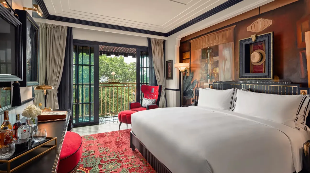 A Premier Room: king bed, red rug, French windows onto the balcony and trees outside