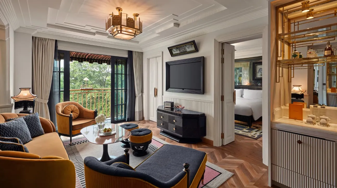 A Premier Suite’s sitting room with velvet armchairs, the bedroom through the door