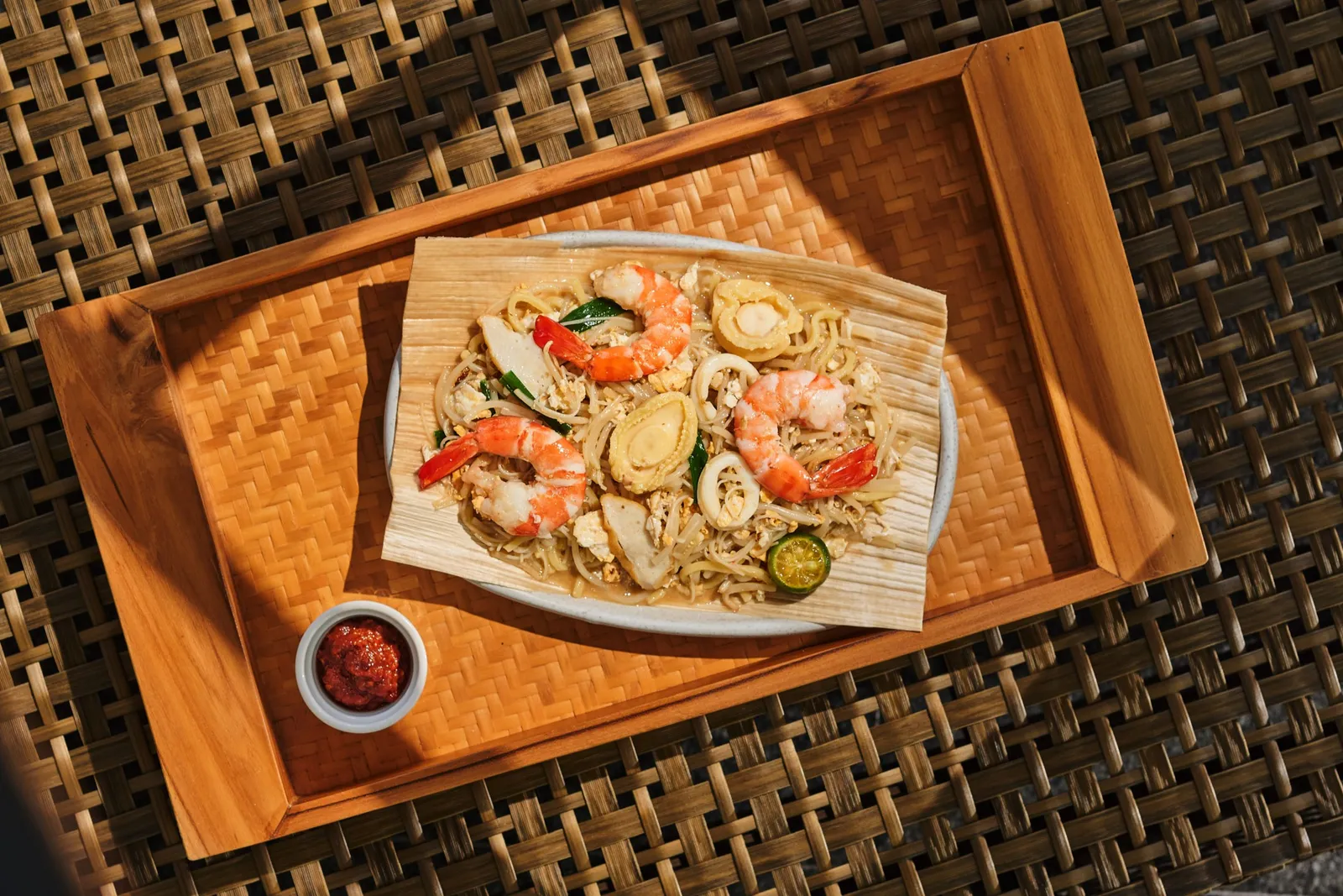 Hokkien mee with prawns at Bob’s Bar, served on a leaf with a small dish of sambal, on a wooden tray.
