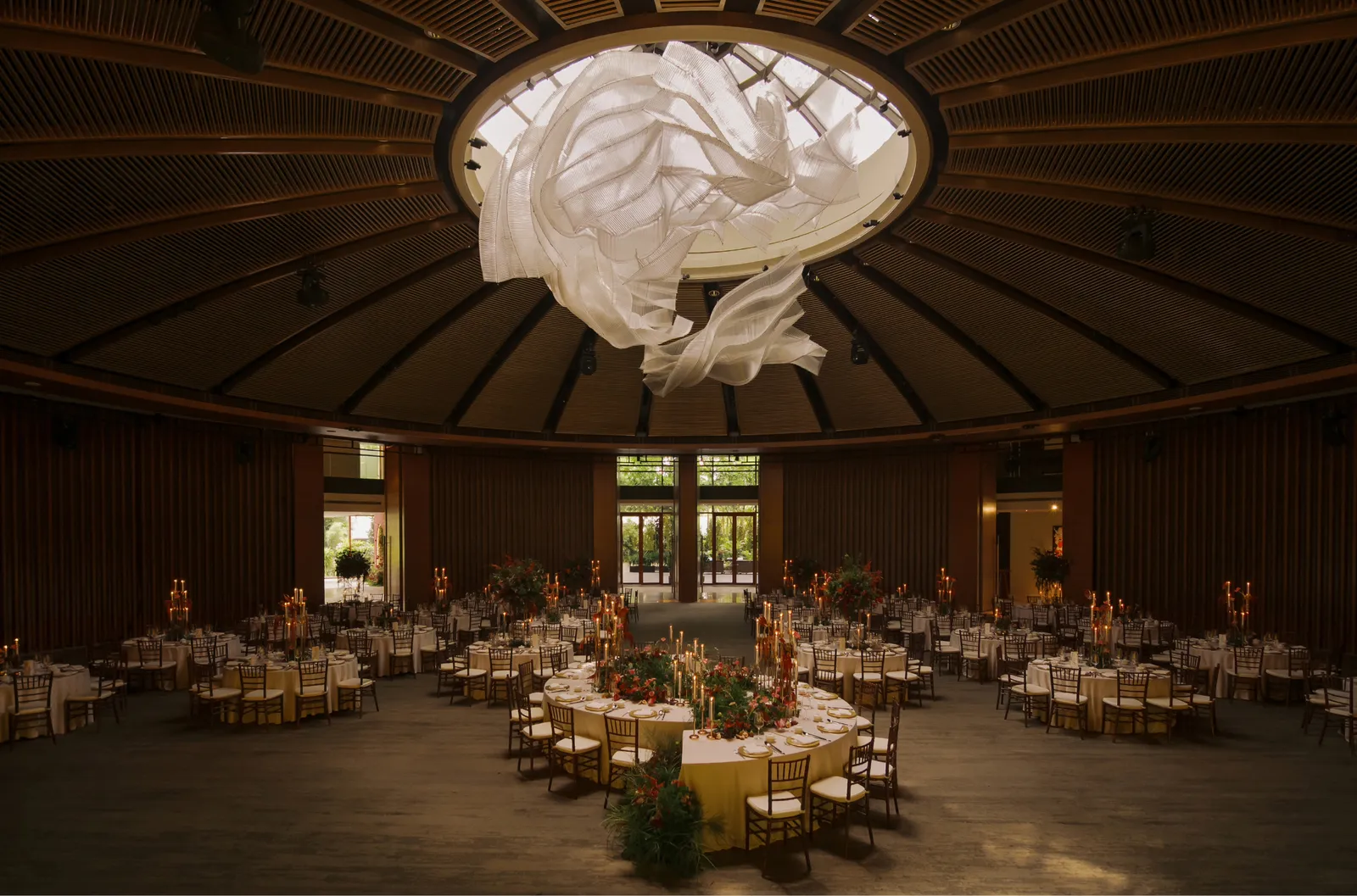 The Grand Ballroom laid for a dinner: round tables under a ribbed circular ceiling with a white sculpture at its centre.