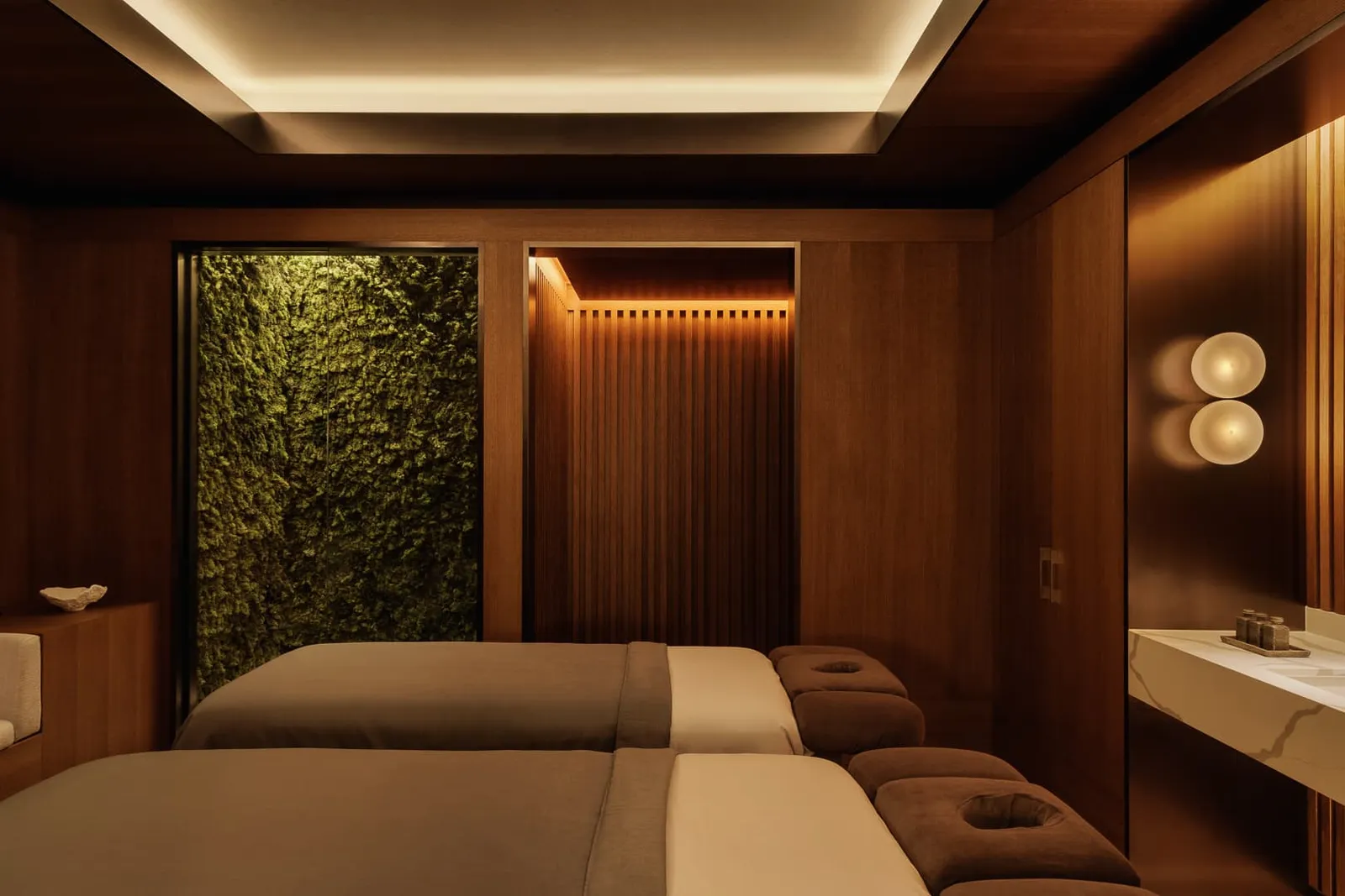 An Auriga Spa treatment room for 2: 2 beds, a moss wall and timber panelling