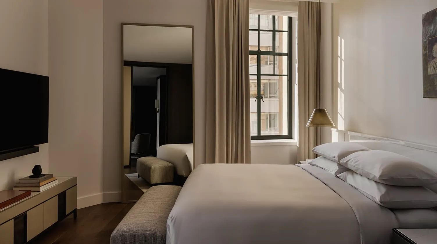 A Deluxe Suite: a lamp and an armchair, the bedroom through an open doorway
