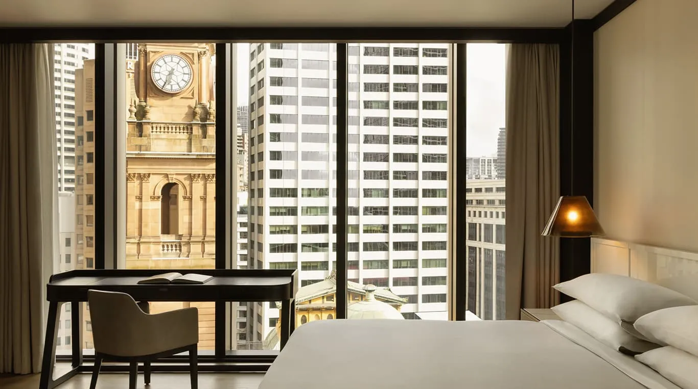 A Tower Room: the bed facing a window onto a sandstone clock tower and office towers