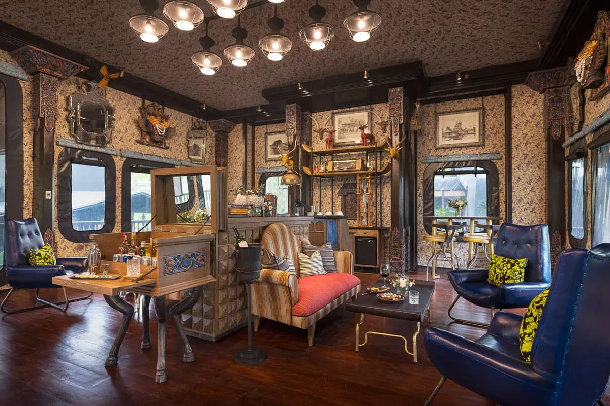 The Officers’ Tent: blue armchairs, a striped sofa, hanging lamps, prints on the walls and wooden portholes onto the forest.