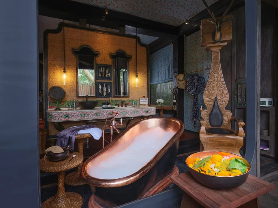 A Keliki Tent’s bathroom: the hammered-copper bath, a bowl of flowers and fruit and the basin under 2 domed mirrors.