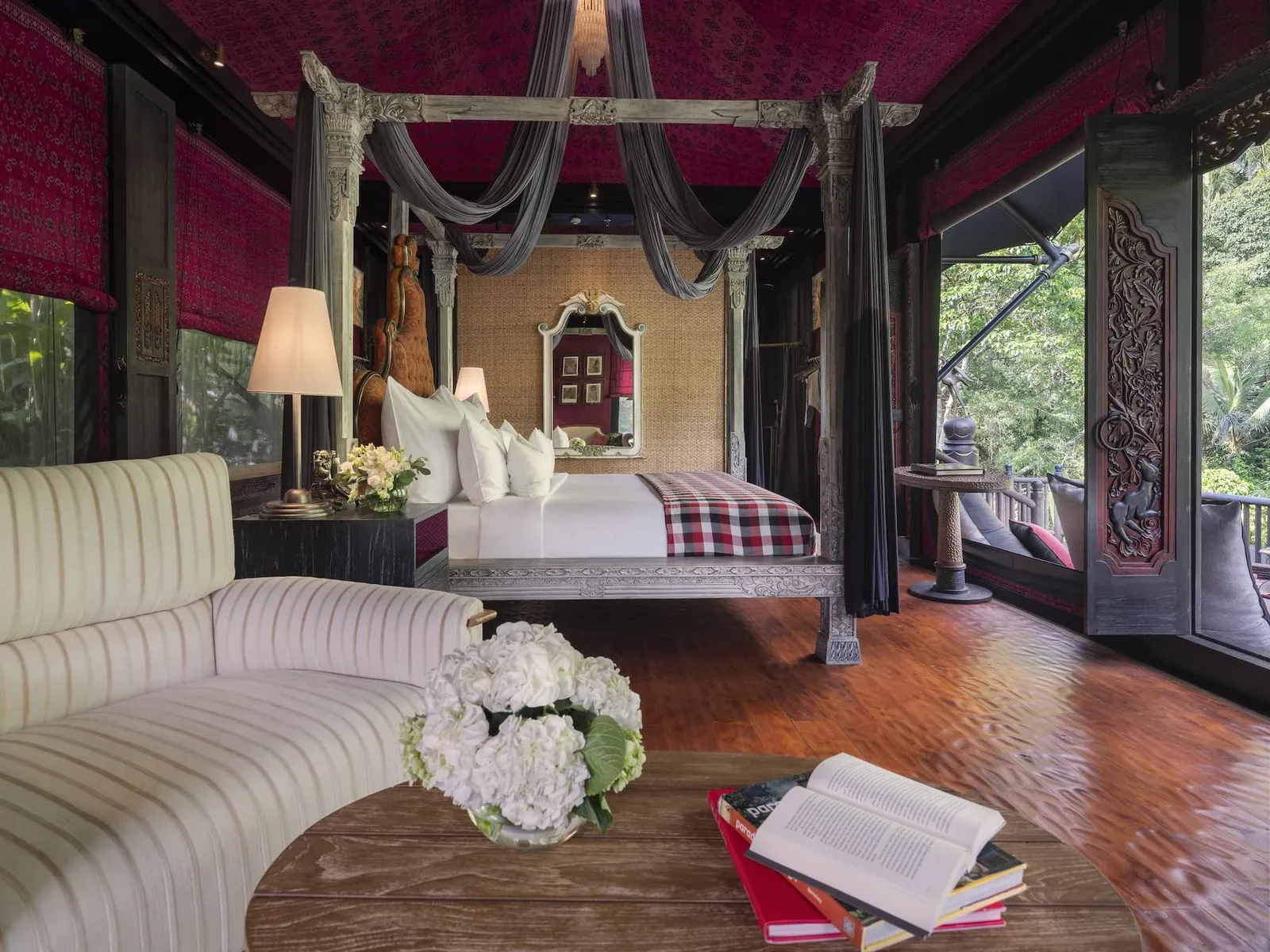 A Valley Tent’s bedroom: the four-poster bed, a curved white sofa, flowers and books on the low table.