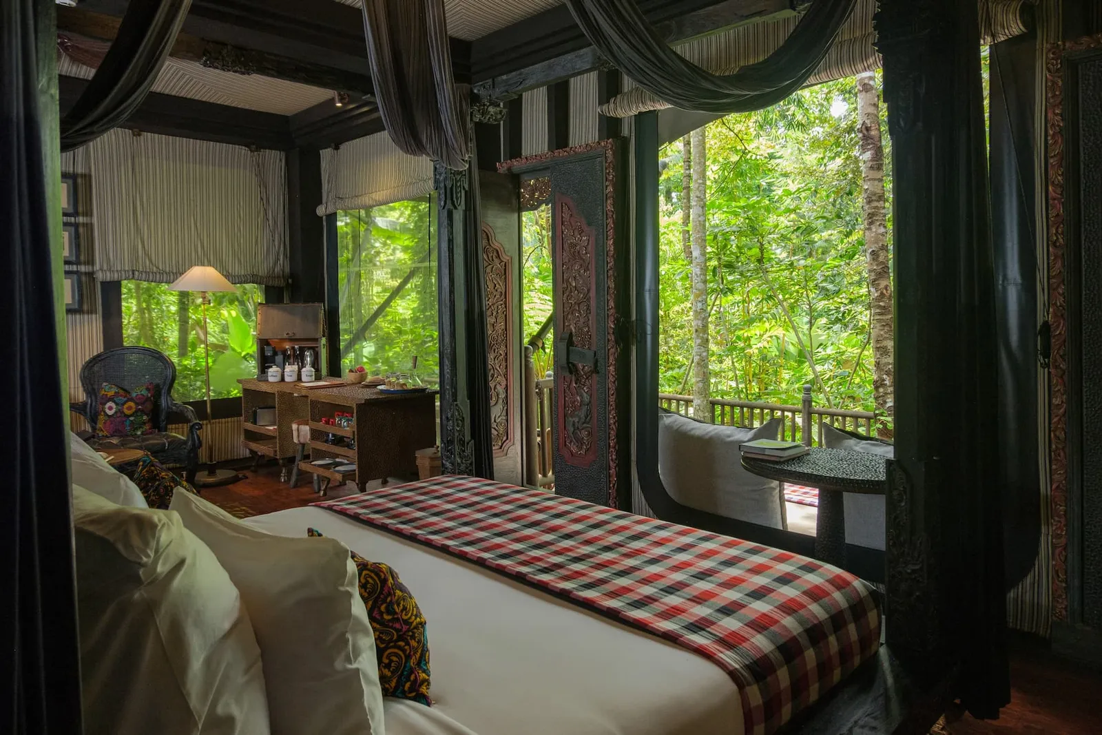 A Terrace Tent’s bedroom: the bed with its red-and-white check cover, the canvas canopy and the windows onto the forest.