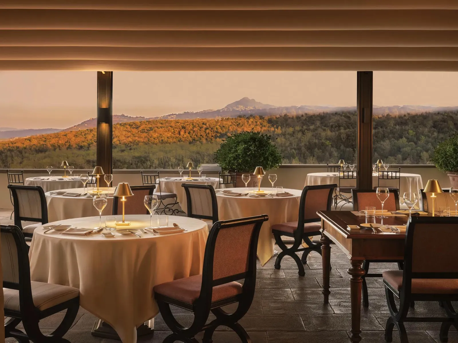 Campo del Drago’s terrace in the evening, tables laid under the awning and the hills rolling out to a mountain on the horizon.