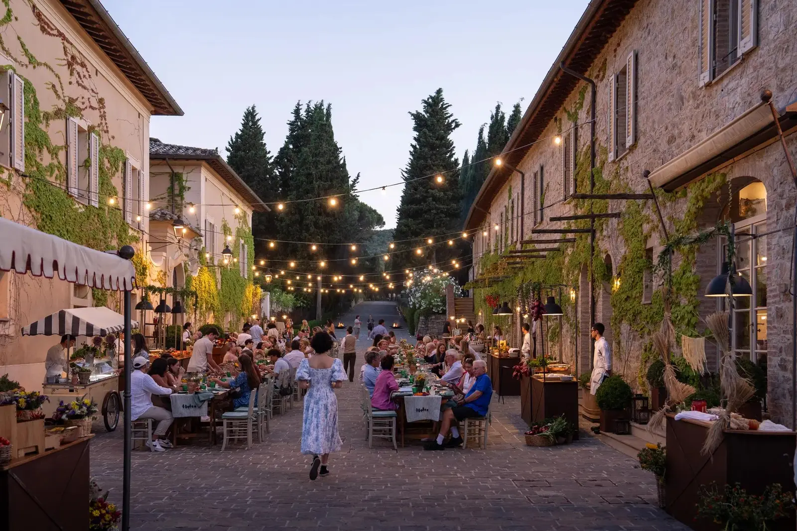 The Festa della Domenica in the borgo’s lane: long tables under strings of lights, guests at dinner between the stone houses.