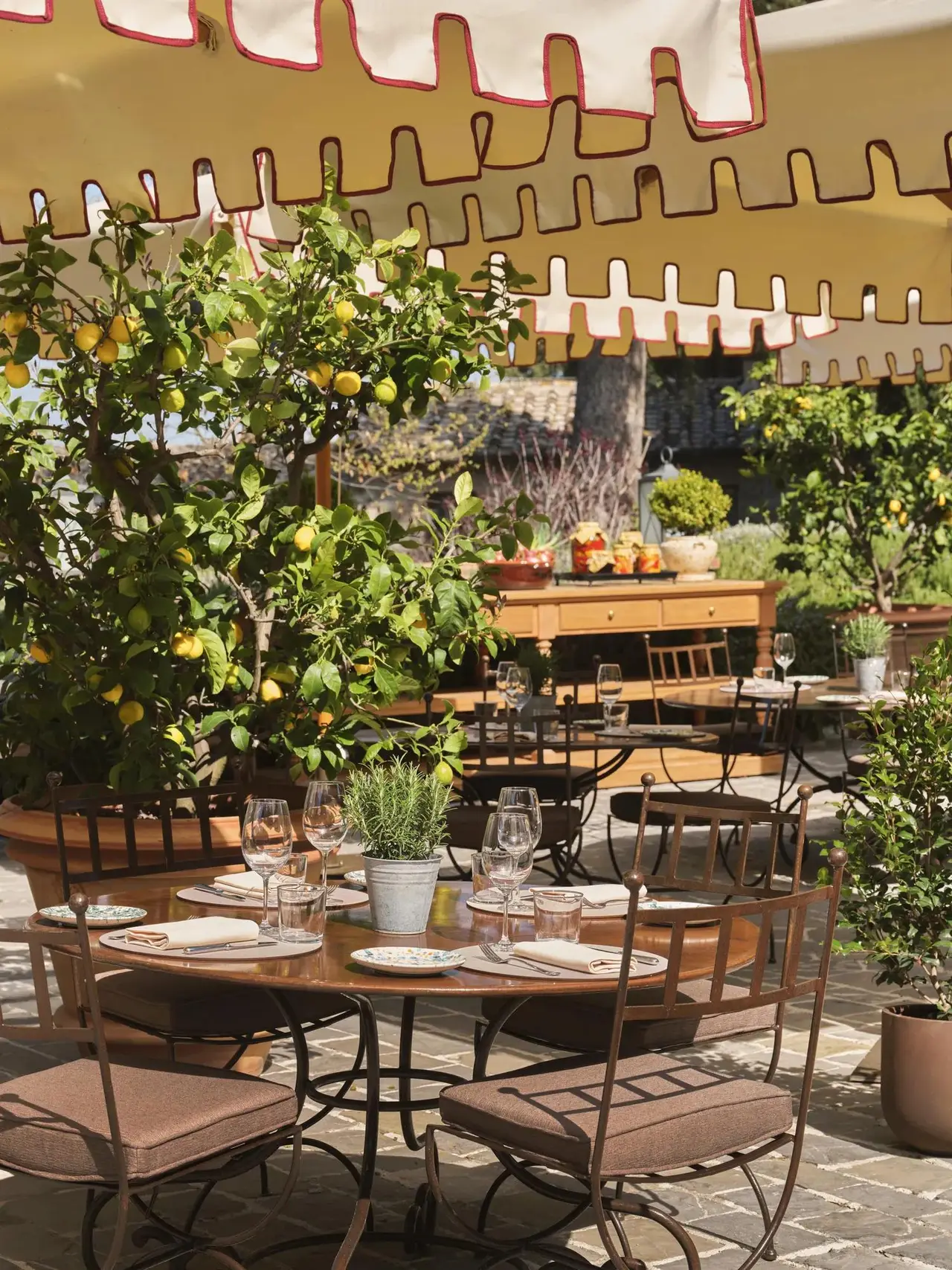Osteria La Canonica’s veranda, tables laid under the striped awning among the lemon trees.