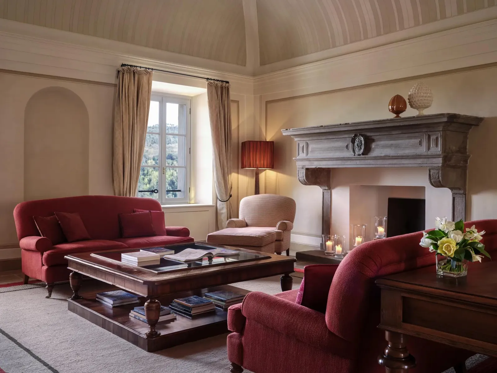 Casa del Vescovo’s drawing room, with its stone fireplace, red sofas and vaulted ceiling.