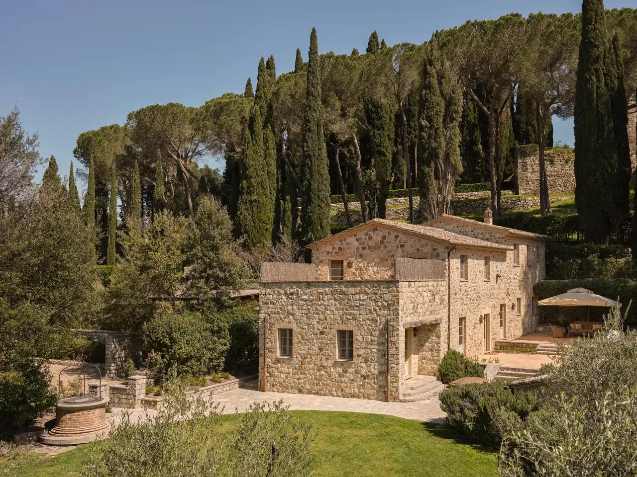 Casa Fontaccia, a 2-storey stone house among pines and cypresses, with the lawn in front.