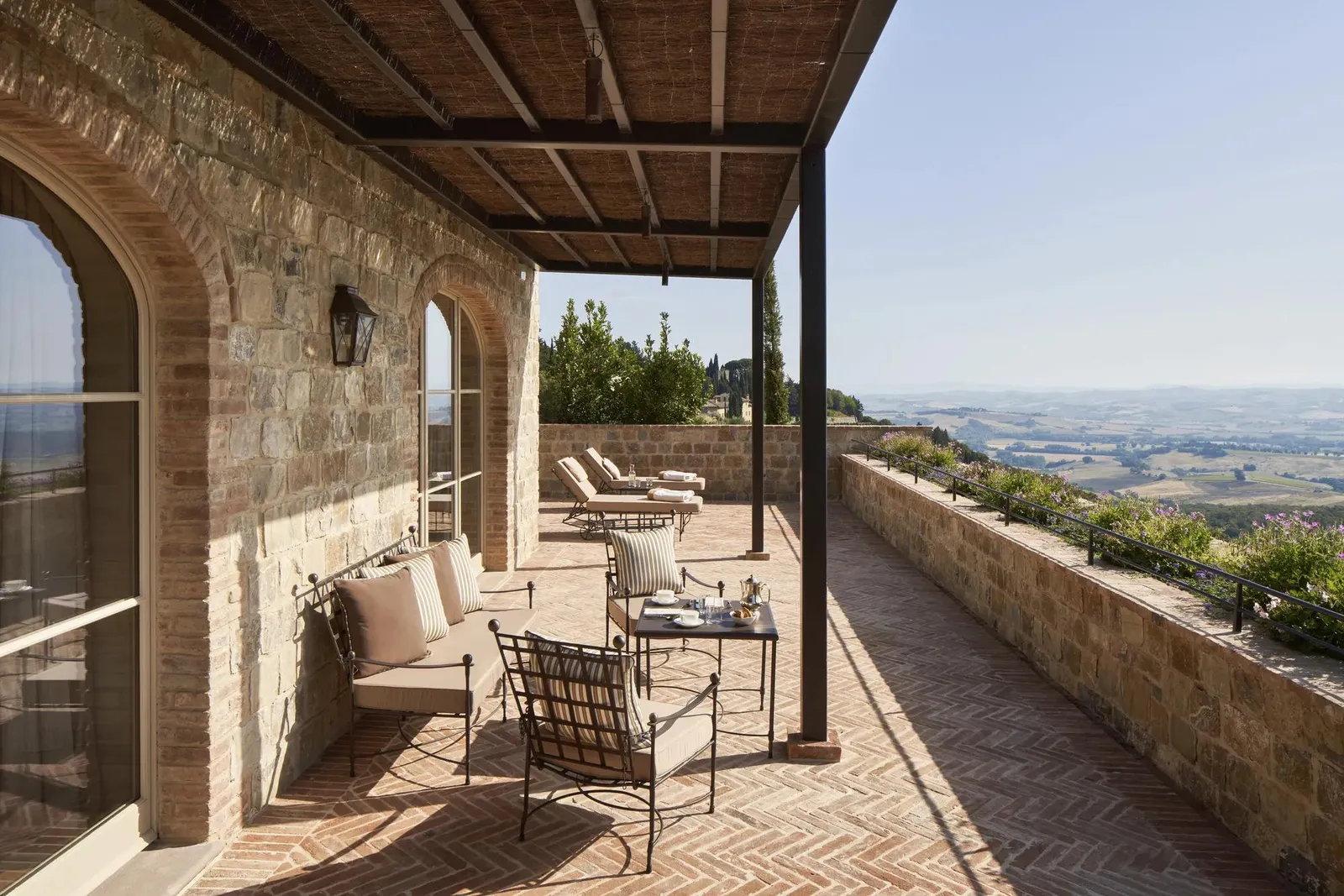 A CdB Suite’s covered terrace, chairs and loungers along the stone wall and the valley below.