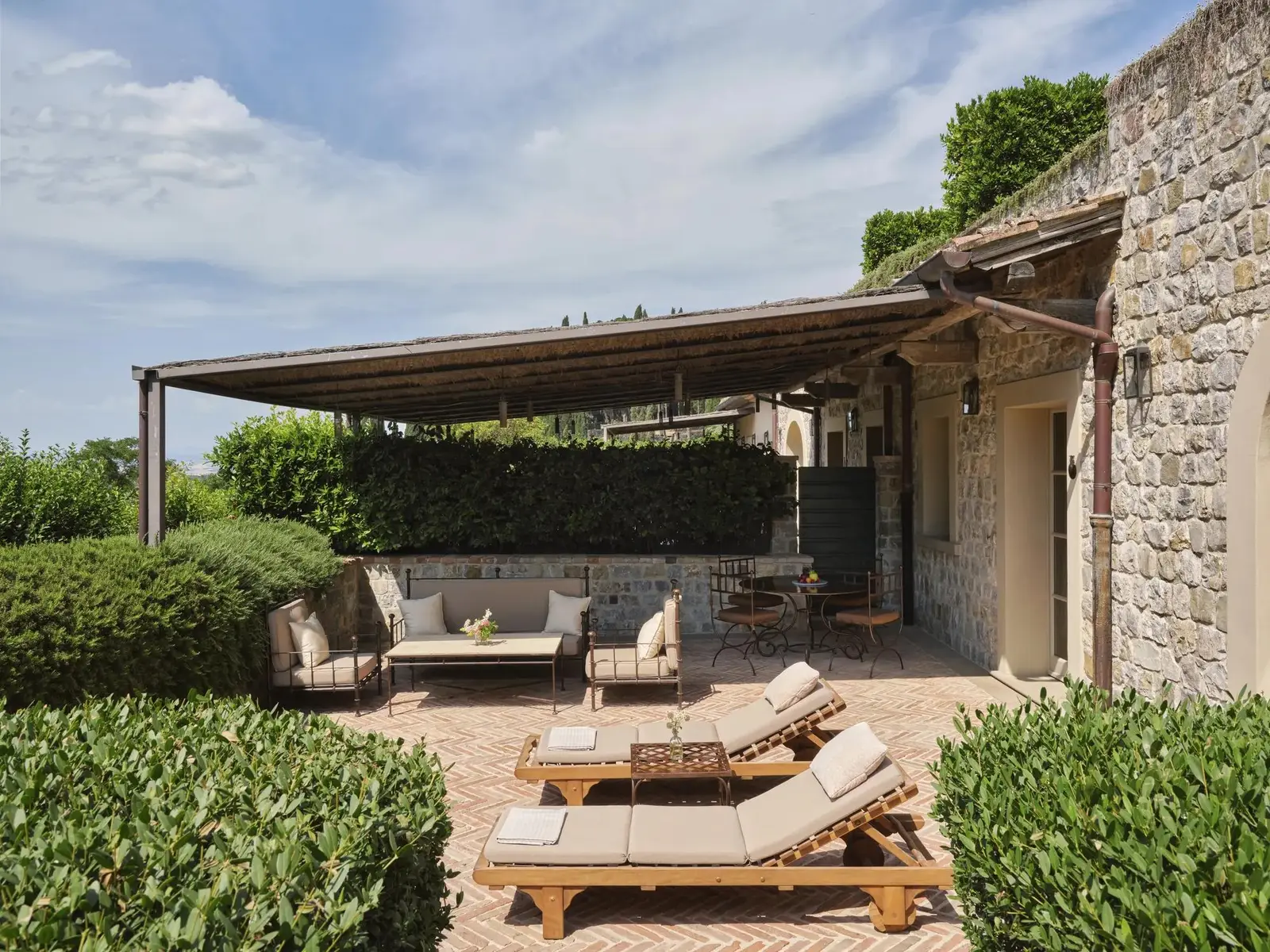 A Terrace Suite’s terrace under its pergola: the outdoor sofas, 2 loungers and the hedges around them.