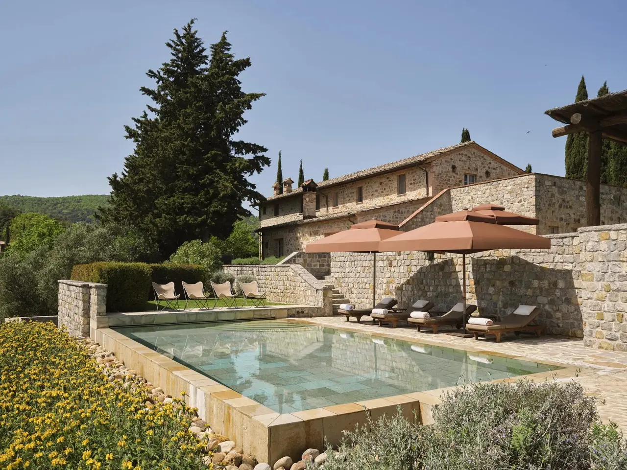 Villa Oliviera’s pool between stone walls, with the parasols and the house above.