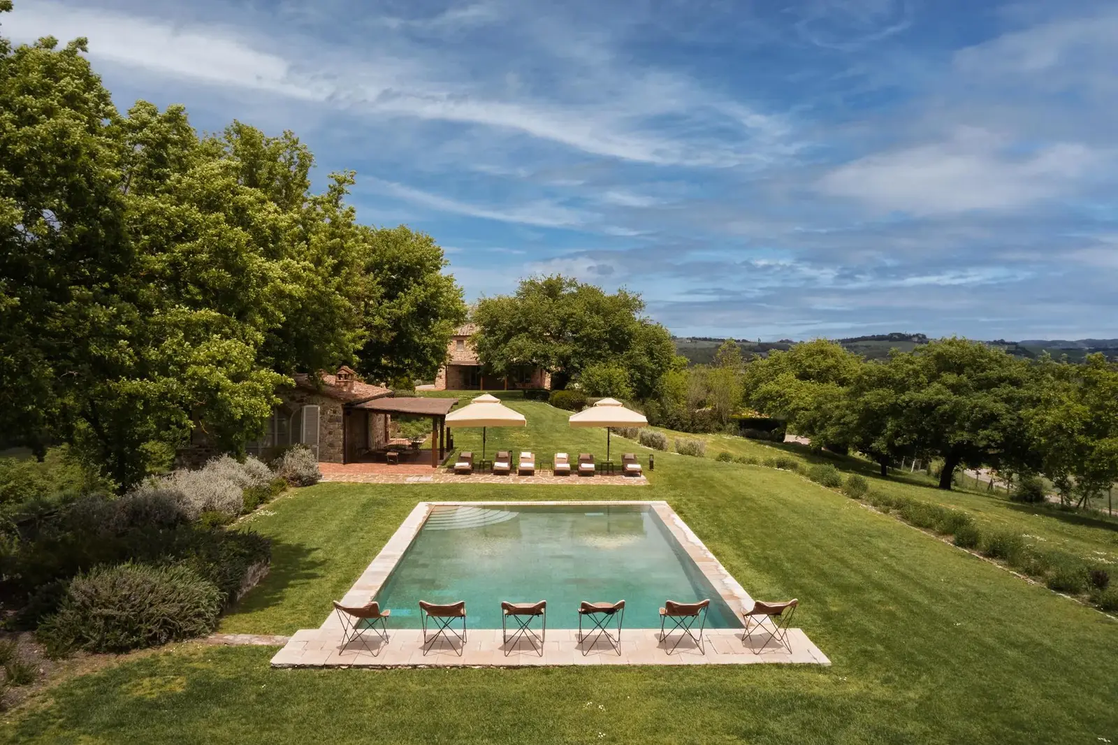 Villa Stabbi’s rectangular pool in the lawn, the loungers and the pool house among the trees.