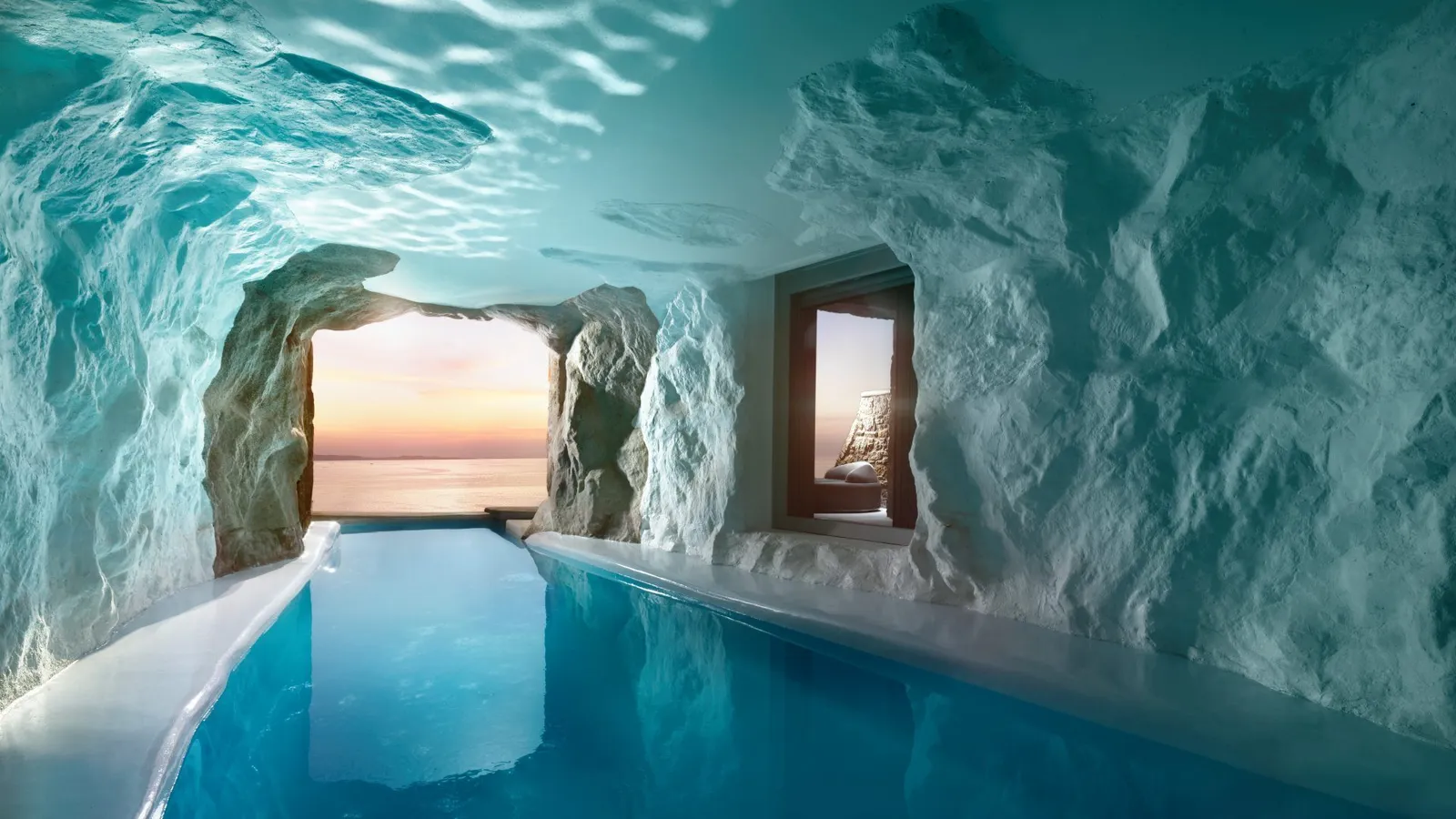 Inside a cave pool: white rock walls, blue water running towards an opening on the sunset and a window into the bedroom.