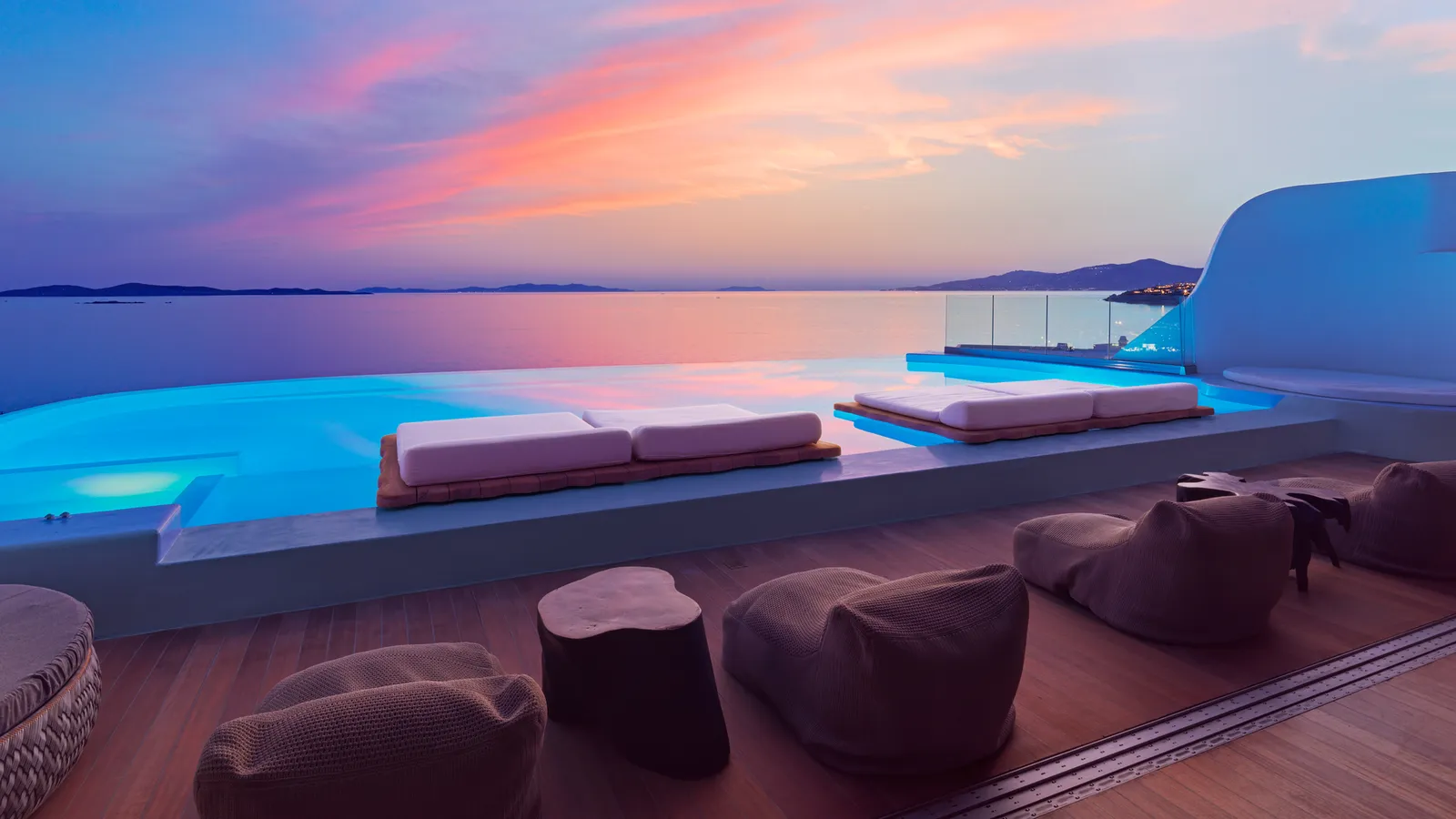 The Diamond Villa’s terrace at sunset, with pouffes, the lit pool and a pink sky above the islands.