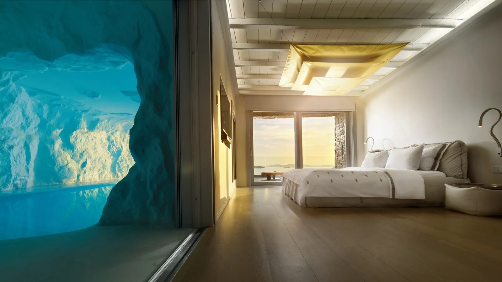 A Cave Pool Suite: on the left the pool in its cave behind glass, on the right the bed and the French window on the sunset.