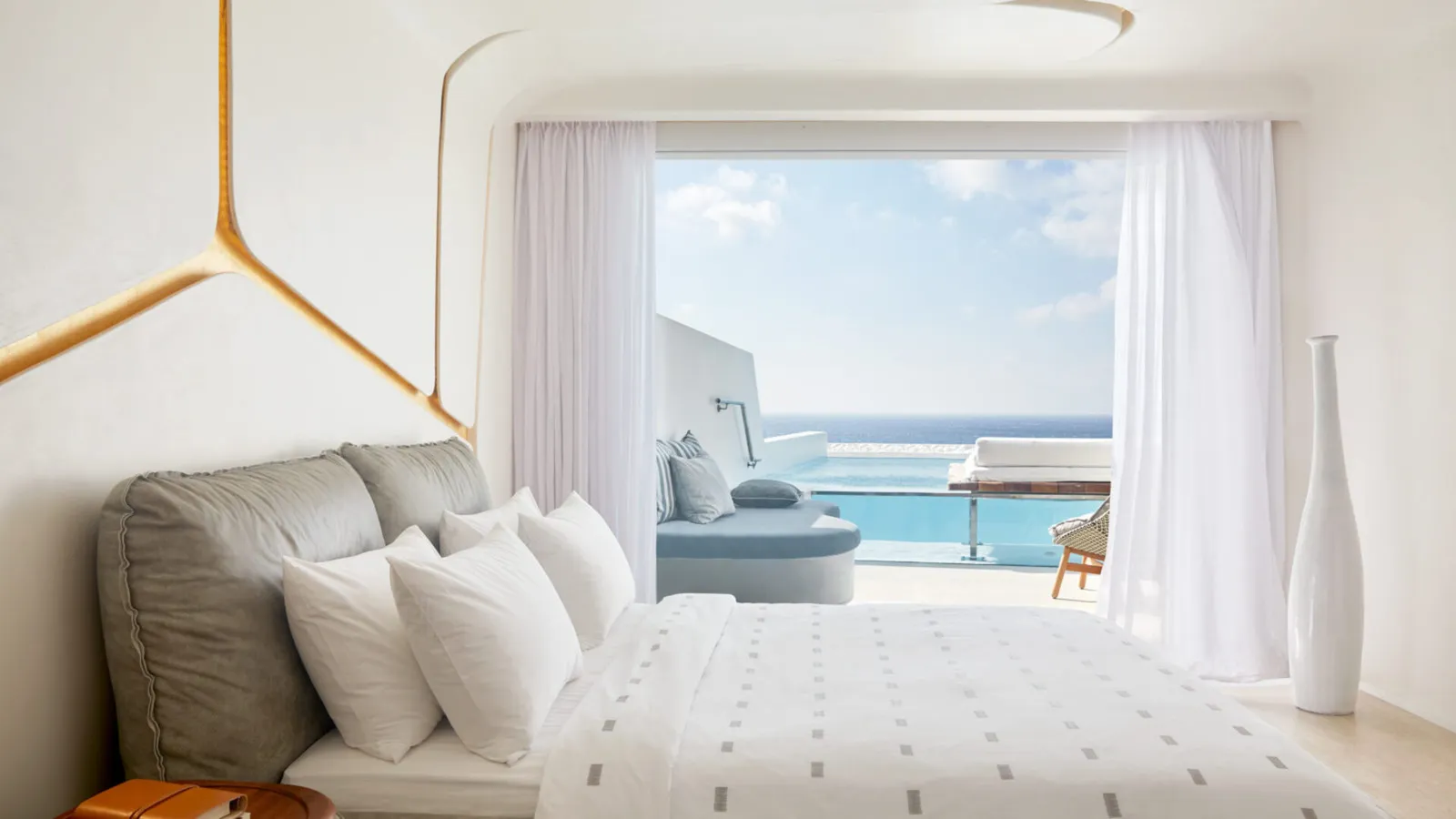 The bed of a Premium Room with Pool, a gold line across the wall and the French window open onto the small pool and the sea.