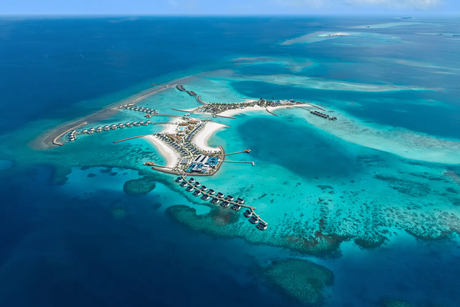 The Atollia from the air: the islands, the rows of water villas and the reef around them