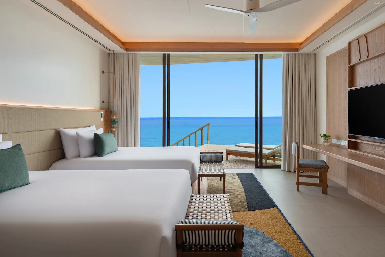 The twin room of a family water villa, the deck and the steps down to the sea