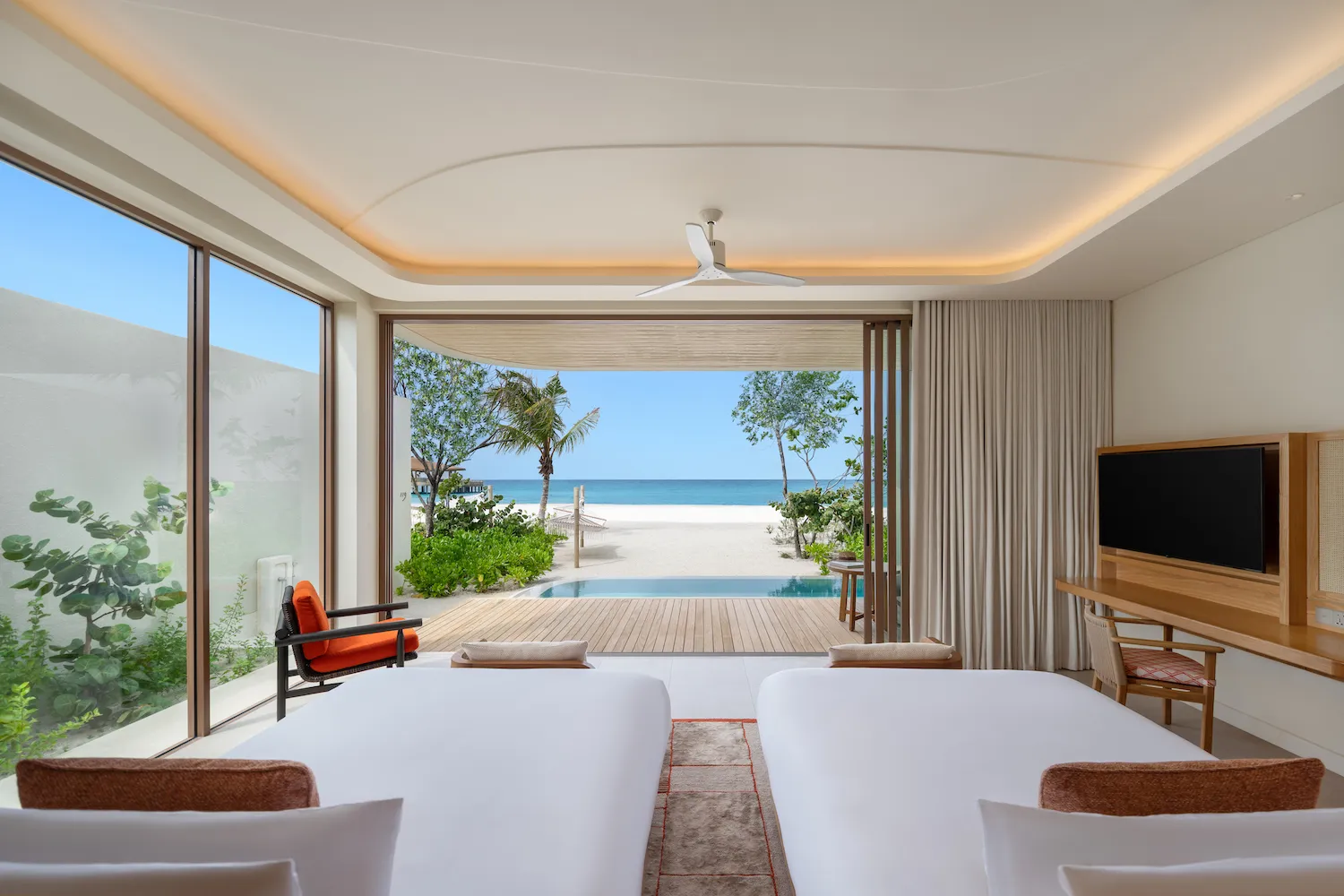 The twin room of a family beach villa, the pool and the sand beyond the glass