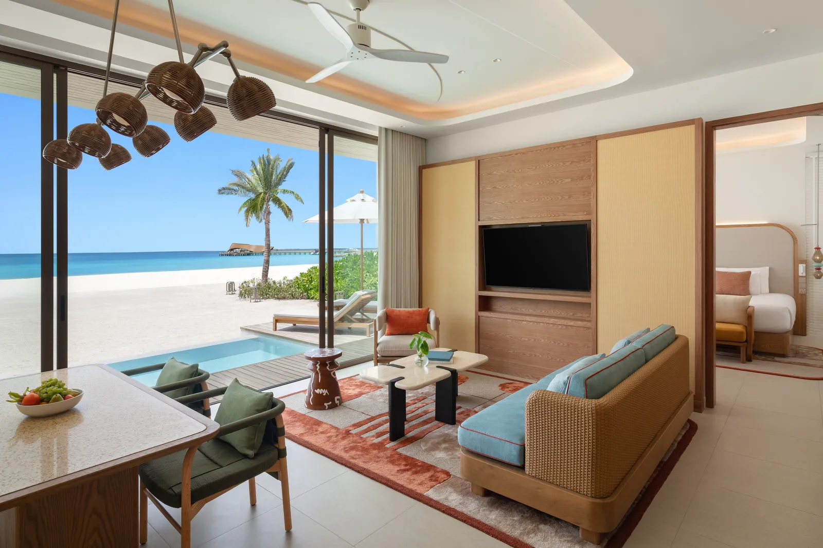 The living room of a Grand Two Bedroom Beach Pool Villa, its dining table, the pool and the beach