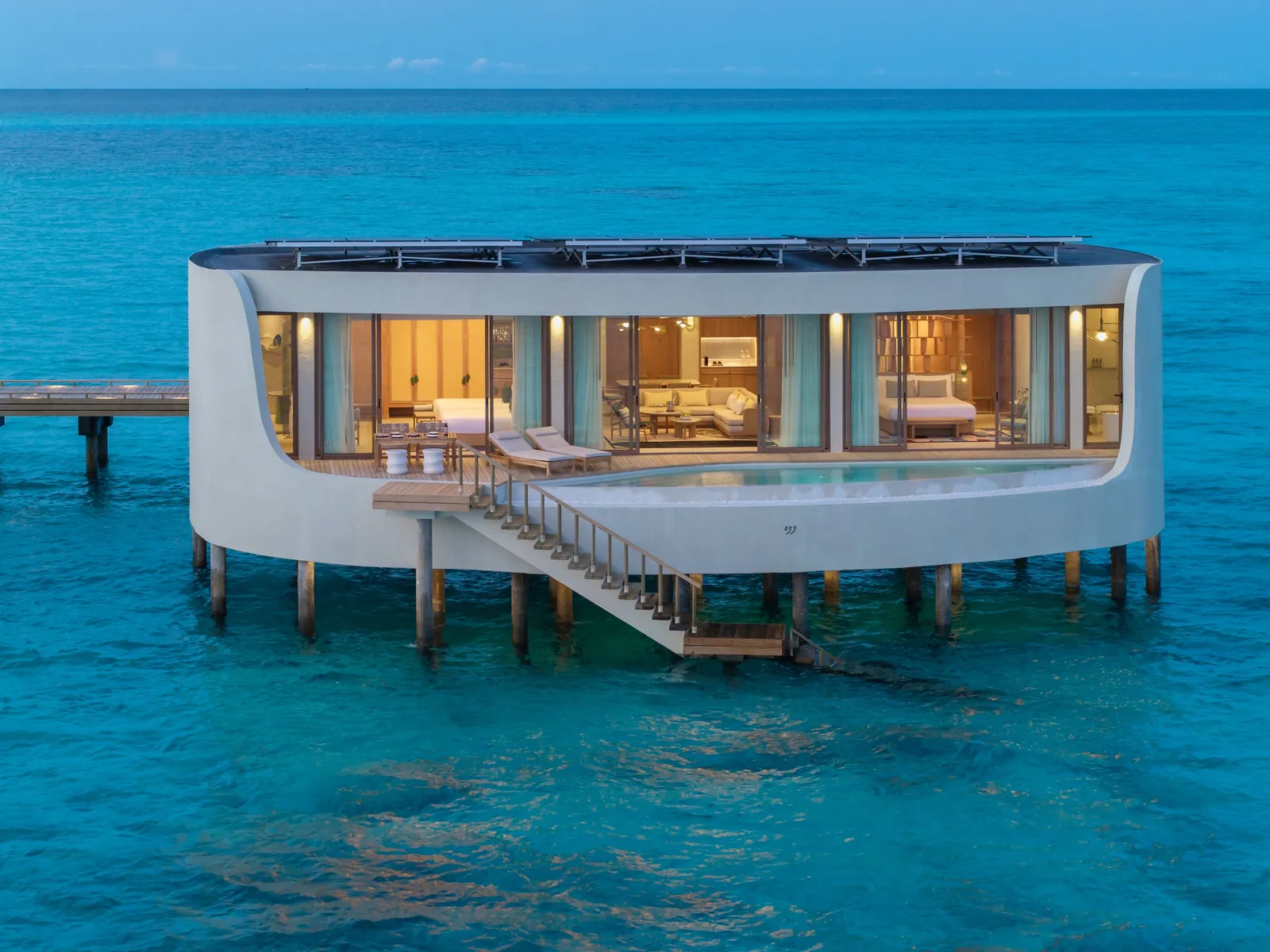 A Grand Two Bedroom Overwater Pool Villa on its stilts, the stairs running down into the water