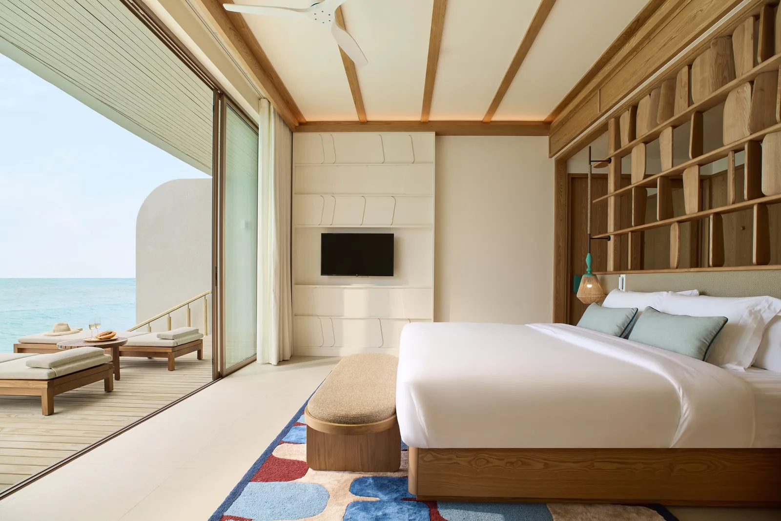 A One-Bedroom Overwater Villa with Jacuzzi: the double bed and the deck with loungers over the sea