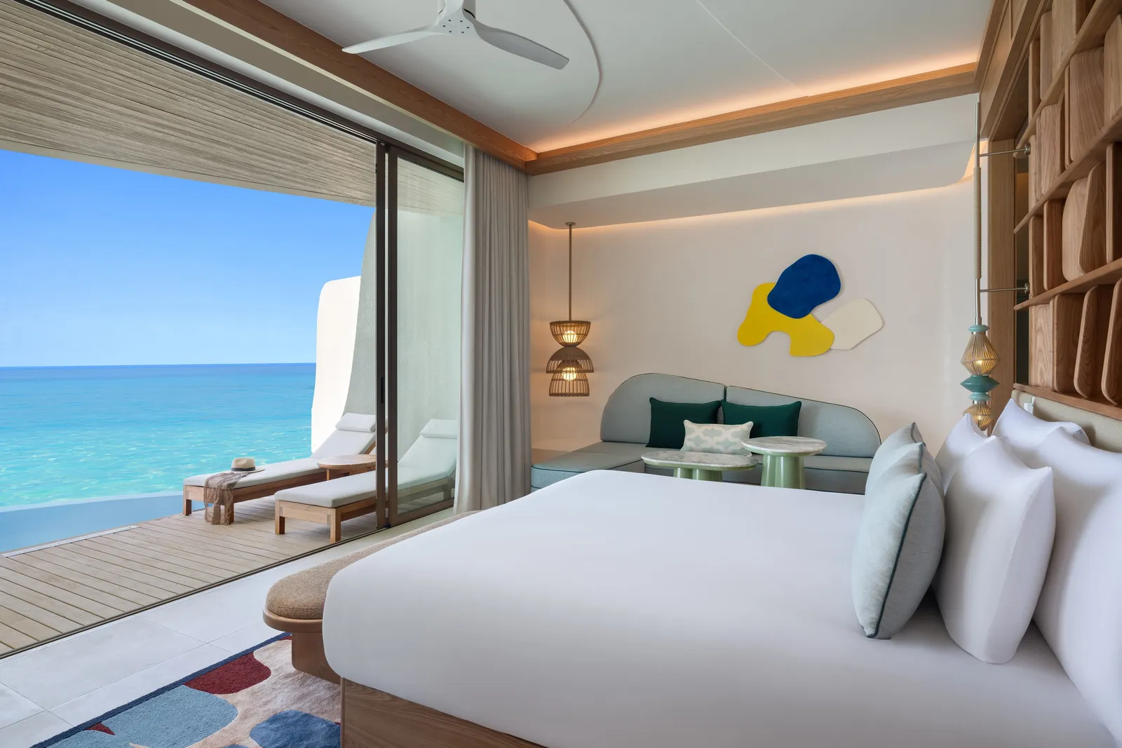 A One-Bedroom Overwater Pool Villa: the bed facing the deck and the pool above the lagoon