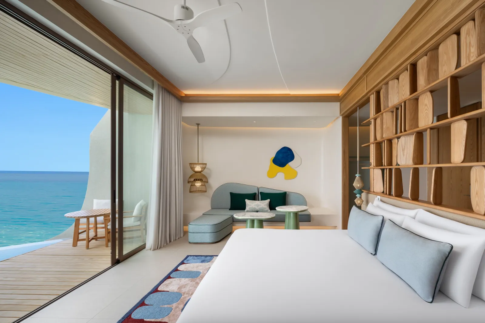 A One-Bedroom Sunset Overwater Pool Villa: the bed, the sofa and the deck open to the sea