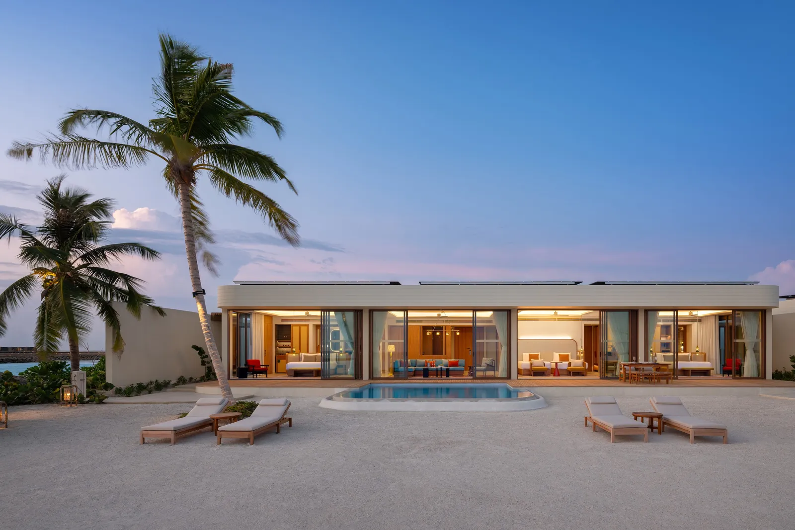 The Three-Bedroom Sunset Beach Pool Residence at dusk, its pool and palms