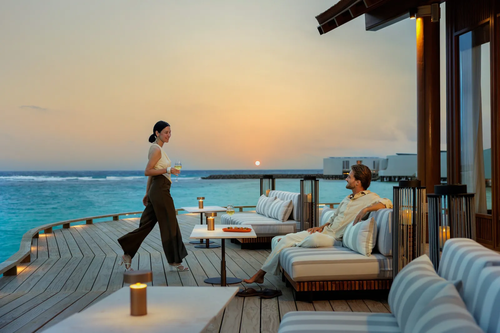 The Club’s terrace at sunset, a couple among the sofas and the sea