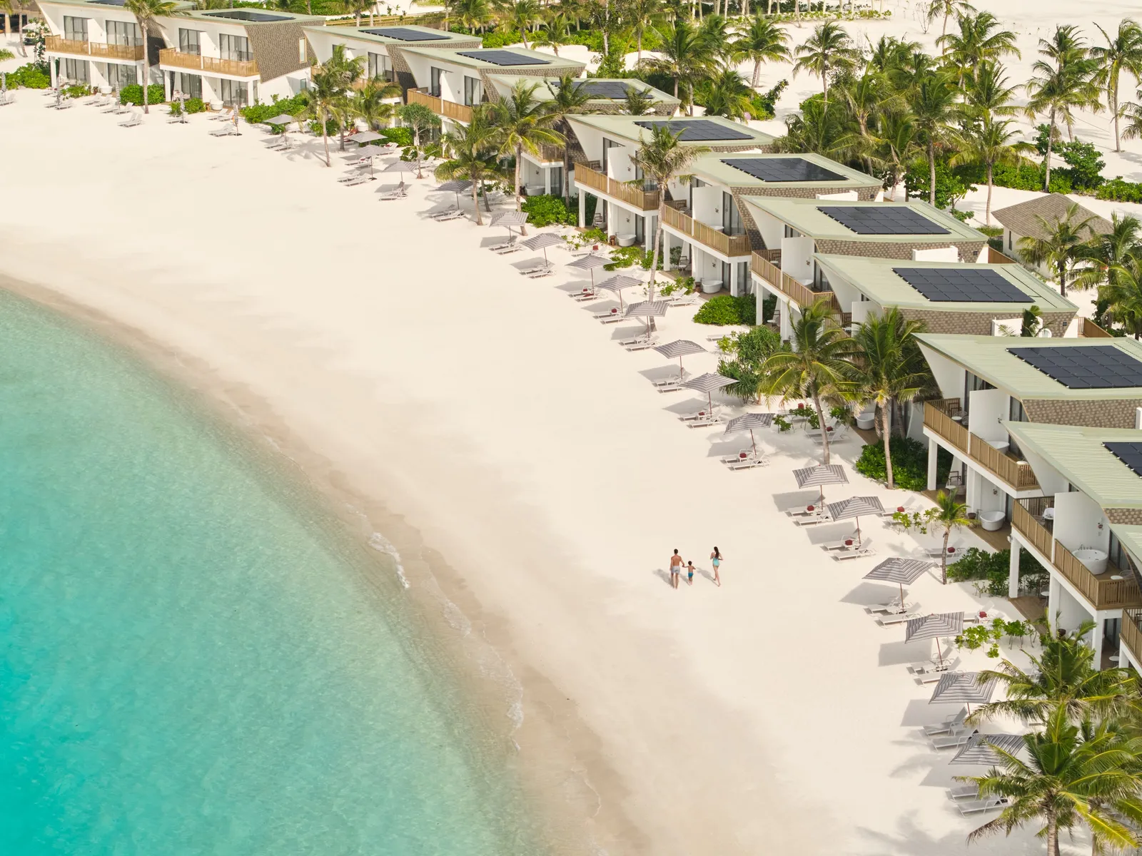 The white beach from above, the row of beachfront rooms on the sand and the shallow water