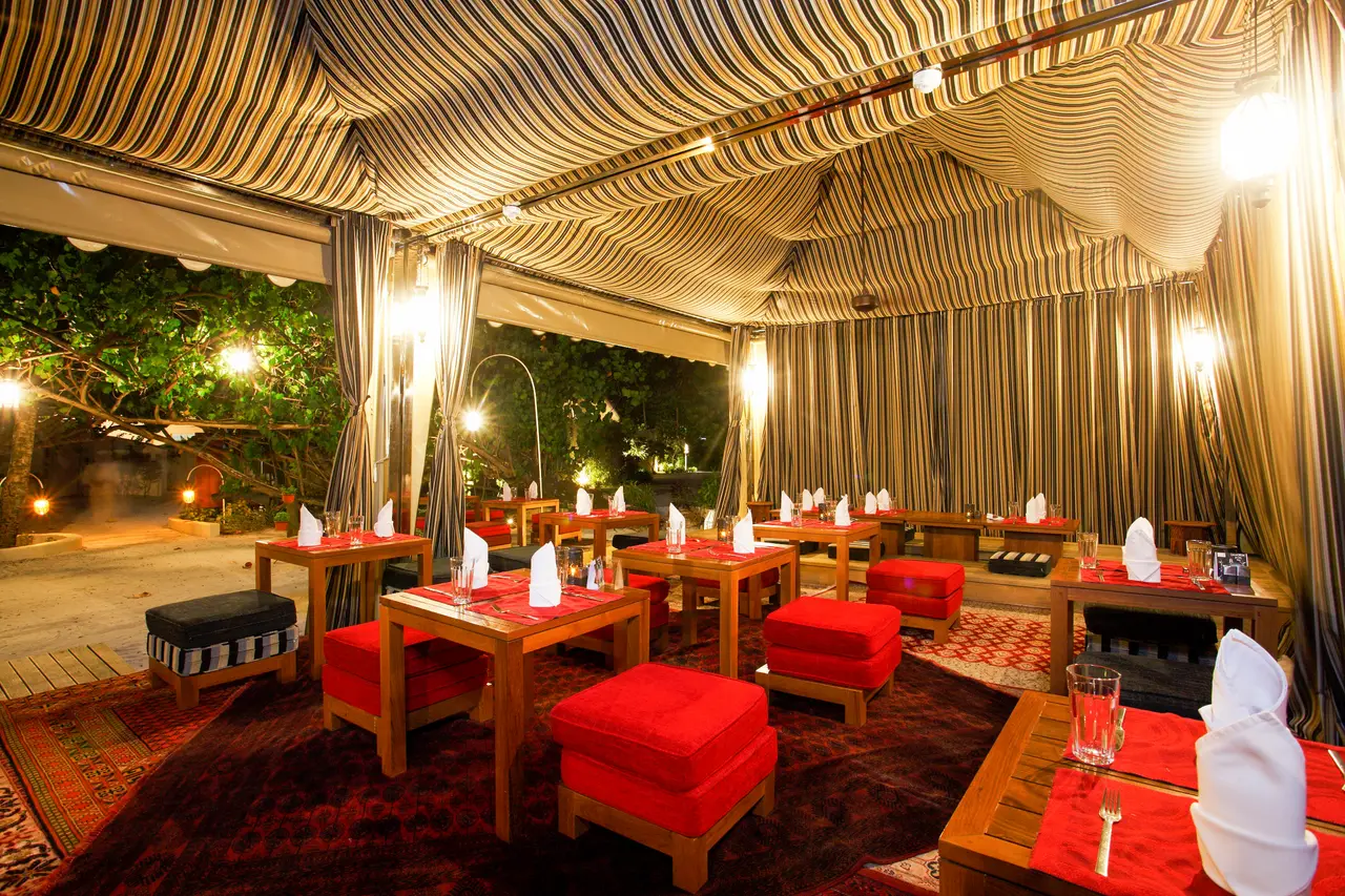Al Khaimah, the Bedouin tent in the garden, its tables laid and red pouffes set out.