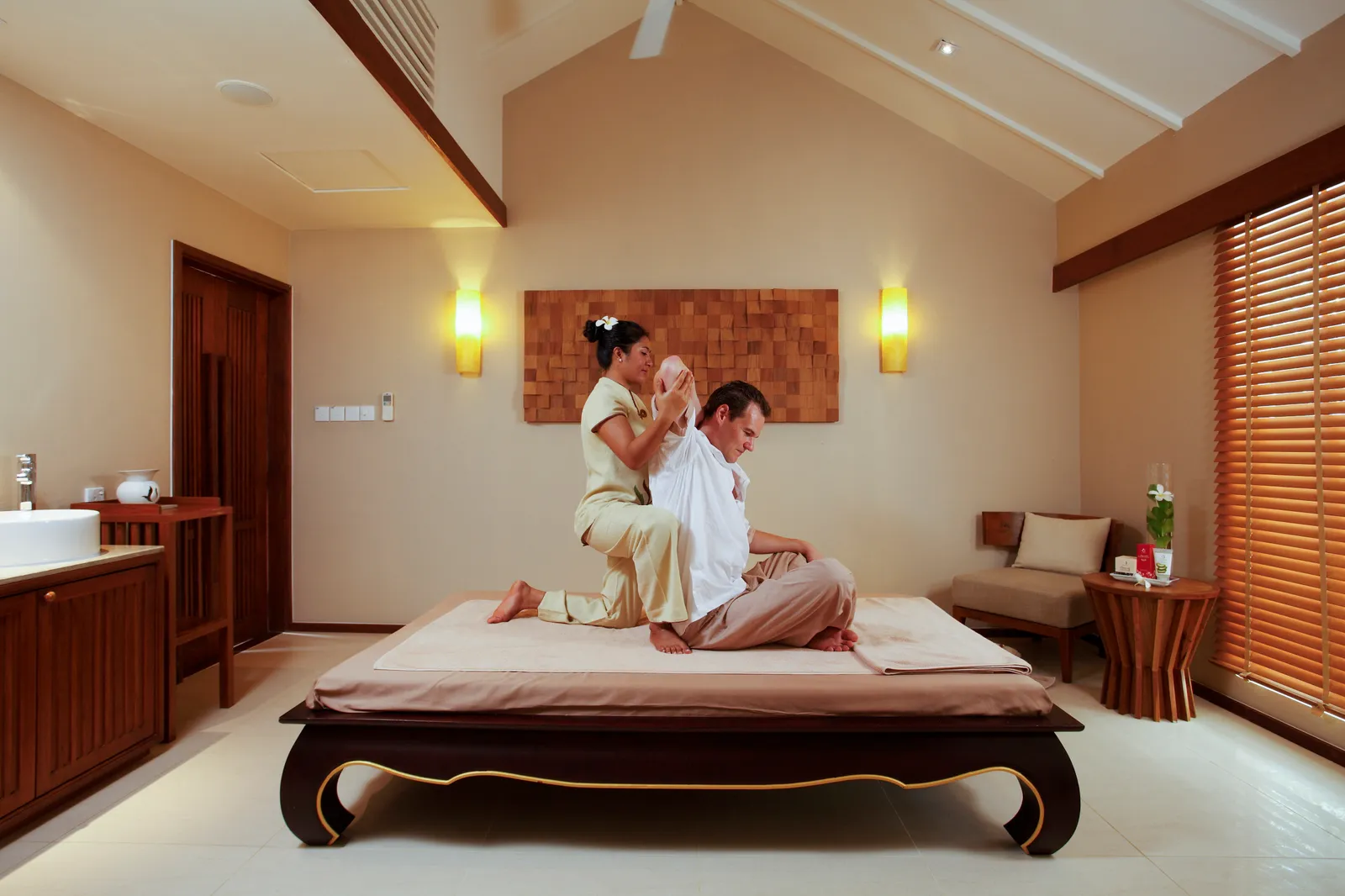 A Thai massage on a low wooden bed in a SPA Cenvaree treatment room.